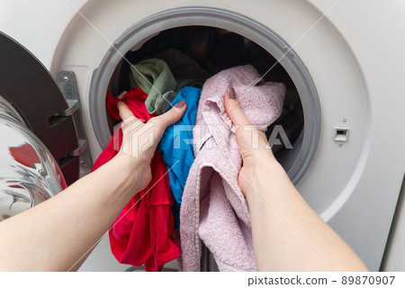 white front-loading washing machine, full of clothes. cleaning laundry. dirty laundry in the washing machine. white front-loading washing machine, full of clothes. cleaning laundry. dirty laundry in the washing machine. 89870907
