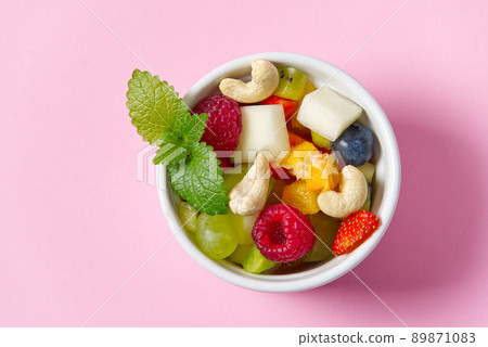 Fresh fruit salad on white bowl. Mixed fruit in white bowl healthy food style. Useful fruit salad of fresh fruits and berries on pink background 89871083