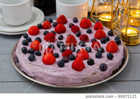Home made Cheesecake with berries. Cheesecake with Strawberry, blueberry and raspberry on grey wooden table decorated with candles and plates. Home made Cheesecake with berries. Cheesecake with Strawberry, blueberry and raspberry on grey wooden table decorated with candles and plates. 89871125