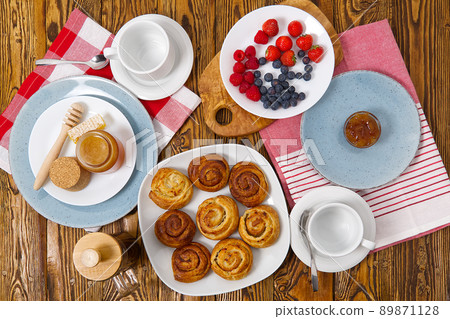 breakfast in the village fresh rolls, coffee, berries and honey laid out on an old brown wooden table. breakfast in the village fresh rolls, coffee, berries and honey laid out on an old brown wooden table. 89871128