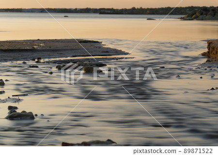 Small stream reaches the sea and freshwater flow through the river. Small stream flows into the sea through the beach.. 89871522