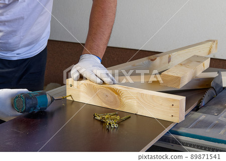 Closeup of professional cabinet makers working with electric circular saw at woodworking workshop. Wood material production. Lumber factory Closeup of professional cabinet makers working with electric circular saw at woodworking workshop. Wood material production. Lumber factory 89871541