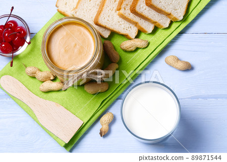 american breakfast milk and peanut butter. Peanut butter, white bread with glass of milk on blue wooden background. 89871544
