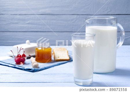 jug and glass of milk on a blue wooden background with cookies. 89871558