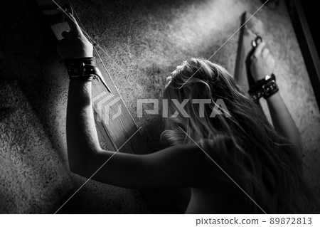 Bound woman slave. Sexy woman in handcuffs. Games for adults in the room BDSM. 89872813