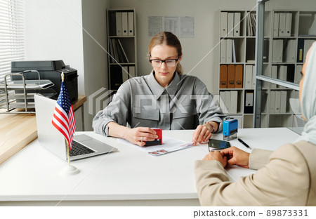 Unrecognizable Muslim woman applying for wrong visa in US embassy getting rejection, consular officer making stamp on it 89873331