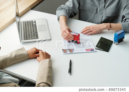 Unrecognizable consular officer refusing to give travel visa to woman putting rejected stamp on application Unrecognizable consular officer refusing to give travel visa to woman putting rejected stamp on application 89873345