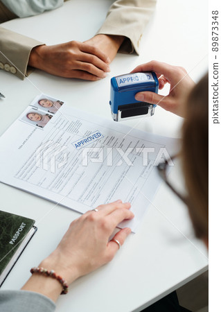 Vertical shot of unrecognizable consular officer approving travel visa for Muslim woman in modern embassy 89873348