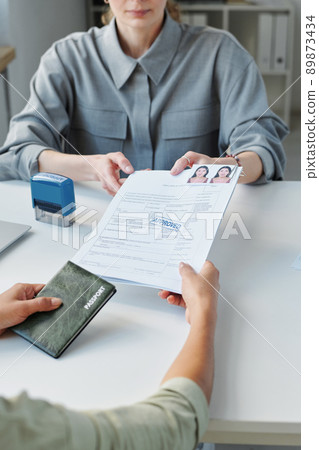 High angle of unrecognizable woman applying for work or visitor visa receiving application form with approval stamp on it 89873434