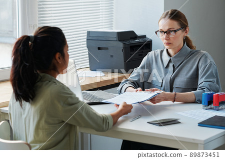 Unrecognizable woman applying for work or visitor visa giving set of documents to professional consular officer 89873451