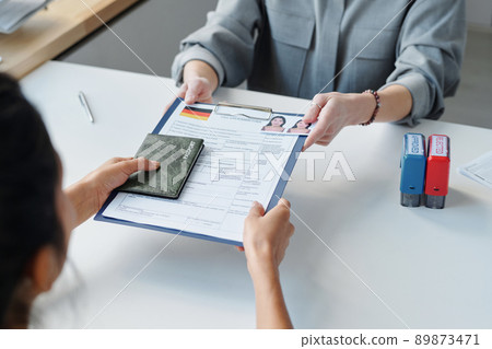 High angle view of unrecognizable woman applying for visa in embassy giving passport and application form to specialist 89873471