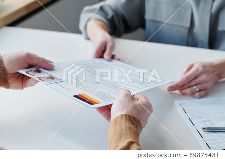 Unrecognizable man sitting in office in embassy or consulate applying for visa giving application form papers to specialist Unrecognizable man sitting in office in embassy or consulate applying for visa giving application form papers to specialist 89873481