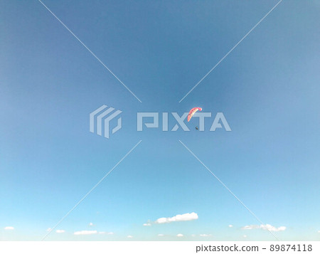 paragliding in the open sky, outdoor activities, travel in a warm country. a bright parachute, a balloon on which a person in a protective suit flies 89874118
