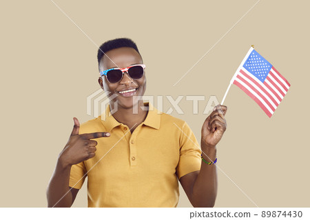 Happy African man who got US citizenship smiles and points at American flag in his hand 89874430