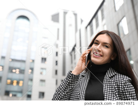Beautiful woman in stylish suit talking on phone outdoors. Space for text 89874971