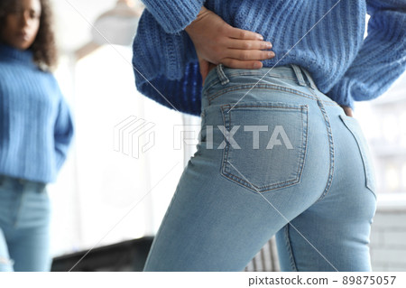 Woman wearing jeans near mirror indoors, closeup 89875057