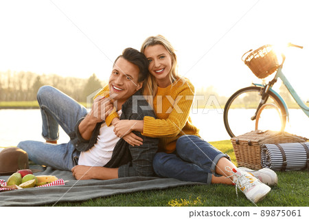 Happy young couple having picnic near lake on sunny day Happy young couple having picnic near lake on sunny day 89875061