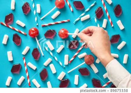 Process of colorful composition creation: unrecognizable man setting out appetizing sweets and colorful drinking straws in a certain order, directly above view Process of colorful composition creation: unrecognizable man setting out appetizing sweets and colorful drinking straws in a certain order, directly above view 89875338