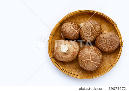 Fresh shiitake mushrooms in bamboo plate on white background. 89875672