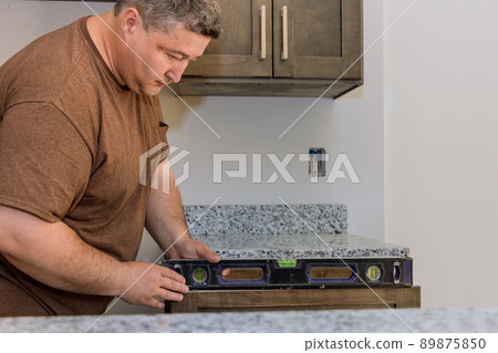 Professional worker assembling leveling countertop for cabinet Professional worker assembling leveling countertop for cabinet 89875850
