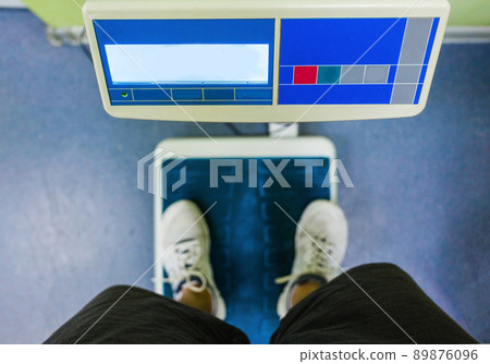 A young man stands on the scales in the gym. 89876096