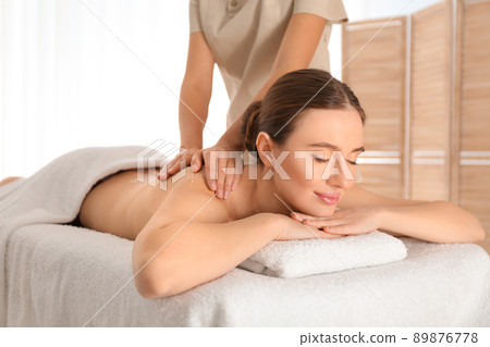 Young woman having body scrubbing procedure with sea salt in spa salon 89876778