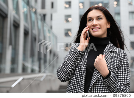 Beautiful woman in stylish suit talking on phone outdoors. Space for text 89876800