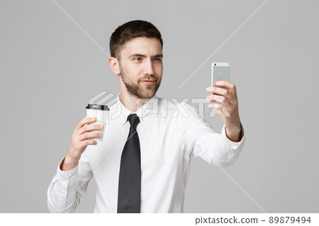 Lifestyle and Business Concept - Portrait of a handsome businessman enjoy taking a selfie with take away cup of coffee. Isolated White background. Copy Space. 89879494