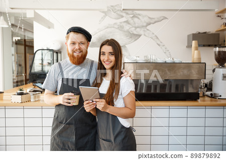 Coffee Business Concept - happy young couple business owners of small coffee shop working and planing on tablet. Coffee Business Concept - happy young couple business owners of small coffee shop working and planing on tablet. 89879892