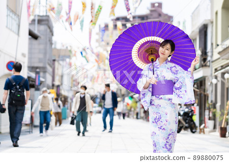 在川越大正羅馬夢通上，身著日式雨傘和鯉魚旗擺姿勢的女人 89880075