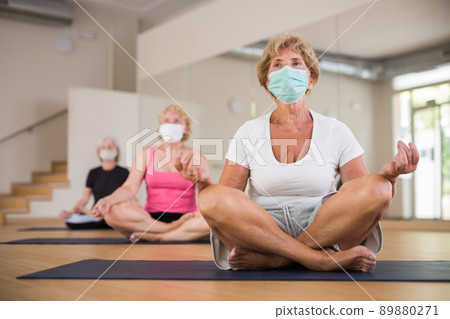 Group of aged ladies in masks sitting in lotus pose Group of aged ladies in masks sitting in lotus pose 89880271
