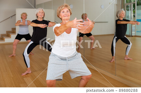 Mature women perform a plie squat while in the position of a ballet stand Mature women perform a plie squat while in the position of a ballet stand 89880288