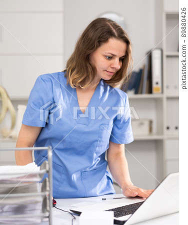 Portrait of female doctor who is working with laptop and documents Portrait of female doctor who is working with laptop and documents 89880426