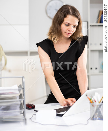 Business woman attentively working behind laptop in modern office 89880447