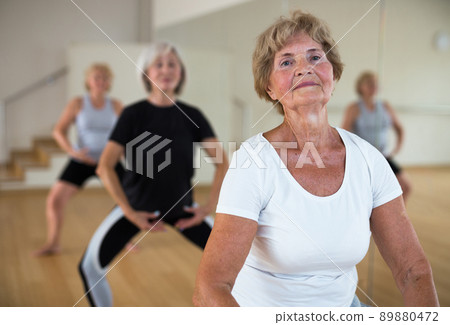 Mature women perform a plie squat while in the position of a ballet stand 89880472