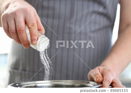 Professional cook hold saltcellar and add salt to soup, chef follow recipe, nutritious meal Professional cook hold saltcellar and add salt to soup, chef follow recipe, nutritious meal 89885533