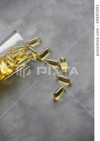 Capsules of omega-3 fatty acids on a gray background. The concept of medicine and a healthy lifestyle. Vertical photo. 89885893