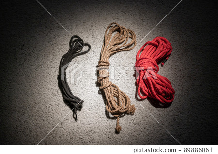Skein of rope for role-playing games on a red leather couch. BDSM concept. A lace for the Japanese art of shibari. No people. Skein of rope for role-playing games on a red leather couch. BDSM concept. A lace for the Japanese art of shibari. No people. 89886061