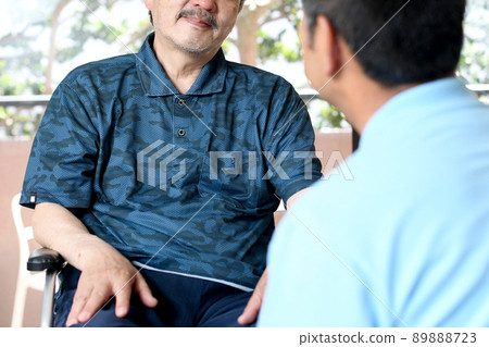 Conversation between an elderly person in a wheelchair and a male caregiver 89888723