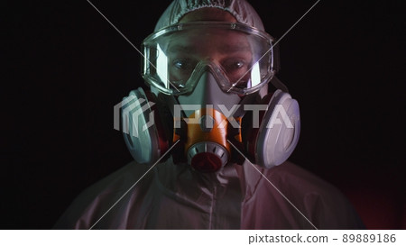 Man in protective costume suit, gas protect medical spray paint mask. Doctor in respirator. Concept health virus coronavirus epidemic. Man in protective costume suit, gas protect medical spray paint mask. Doctor in respirator. Concept health virus coronavirus epidemic. 89889186