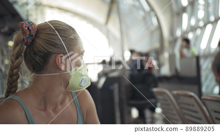 Woman caucasian at airport with wearing protective medical mask on head against the background of the plane. Coronavirus sars-cov-2 covid-19. Woman caucasian at airport with wearing protective medical mask on head against the background of the plane. Coronavirus sars-cov-2 covid-19. 89889205