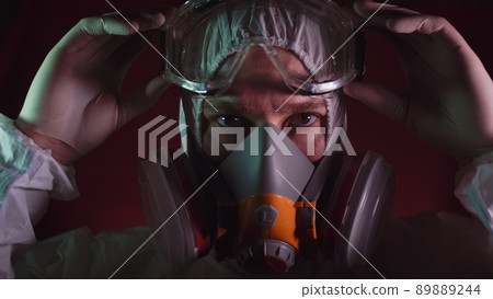 Man in protective costume suit, gas protect medical spray paint mask. Doctor in respirator. Concept health virus coronavirus epidemic. Man in protective costume suit, gas protect medical spray paint mask. Doctor in respirator. Concept health virus coronavirus epidemic. 89889244