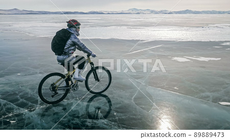 Woman is riding bicycle on the ice. Tires on bike are covered wi Woman is riding bicycle on the ice. Tires on bike are covered wi 89889473