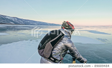 Woman is riding bicycle on the ice. Tires on bike are covered wi 89889484