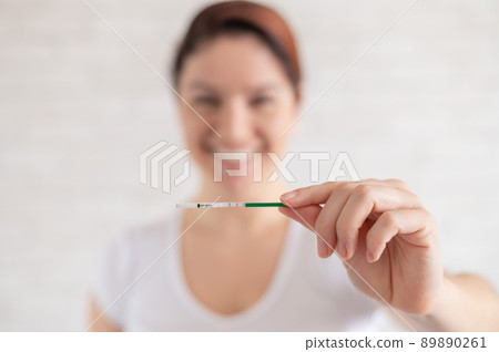 Happy woman shows a positive pregnancy test. The concept of female fertility. Human chorionic gonadotropin. Two stripes expecting a baby. Happy woman shows a positive pregnancy test. The concept of female fertility. Human chorionic gonadotropin. Two stripes expecting a baby. 89890261