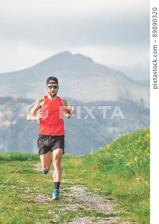 An athlete runs on a mountain dirt road 89890320