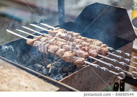 Meat pieces strung on metal skewers on the grill at sunset 89890544