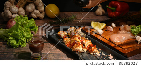 Grilled skewers of chicken, bell peppers, tomatoes, onion and barbecue sauce on wooden background 89892028