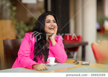 Portrait of a young and stylish Indian woman sitting in a cafe and enjoying a drink while waiting for friends, colleagues or customers Portrait of a young and stylish Indian woman sitting in a cafe and enjoying a drink while waiting for friends, colleagues or customers 89892089