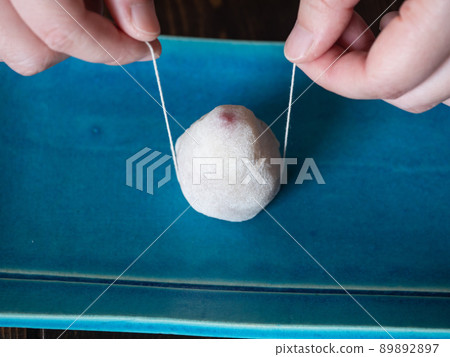 用線將水果大福切成兩半的地方。用化肥和白豆沙包裹鮮紅色的草莓製成的日式甜點。 89892897